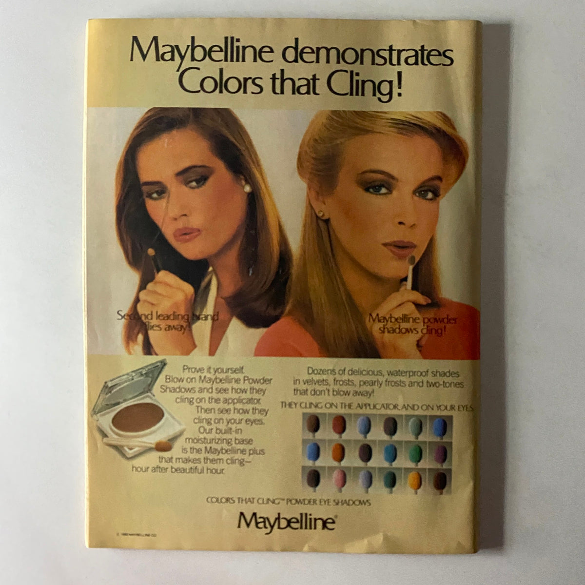 Maybelline advertisement demonstrating powder eye shadows, highlighting their waterproof features and showcasing two models with elegant eye makeup.