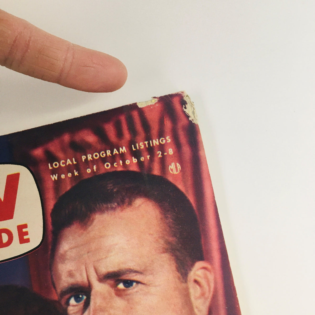 Close-up of the corner of TV Guide Magazine October 2 1954, Vol 2 #40, featuring weathered edges and local program listings for the week.