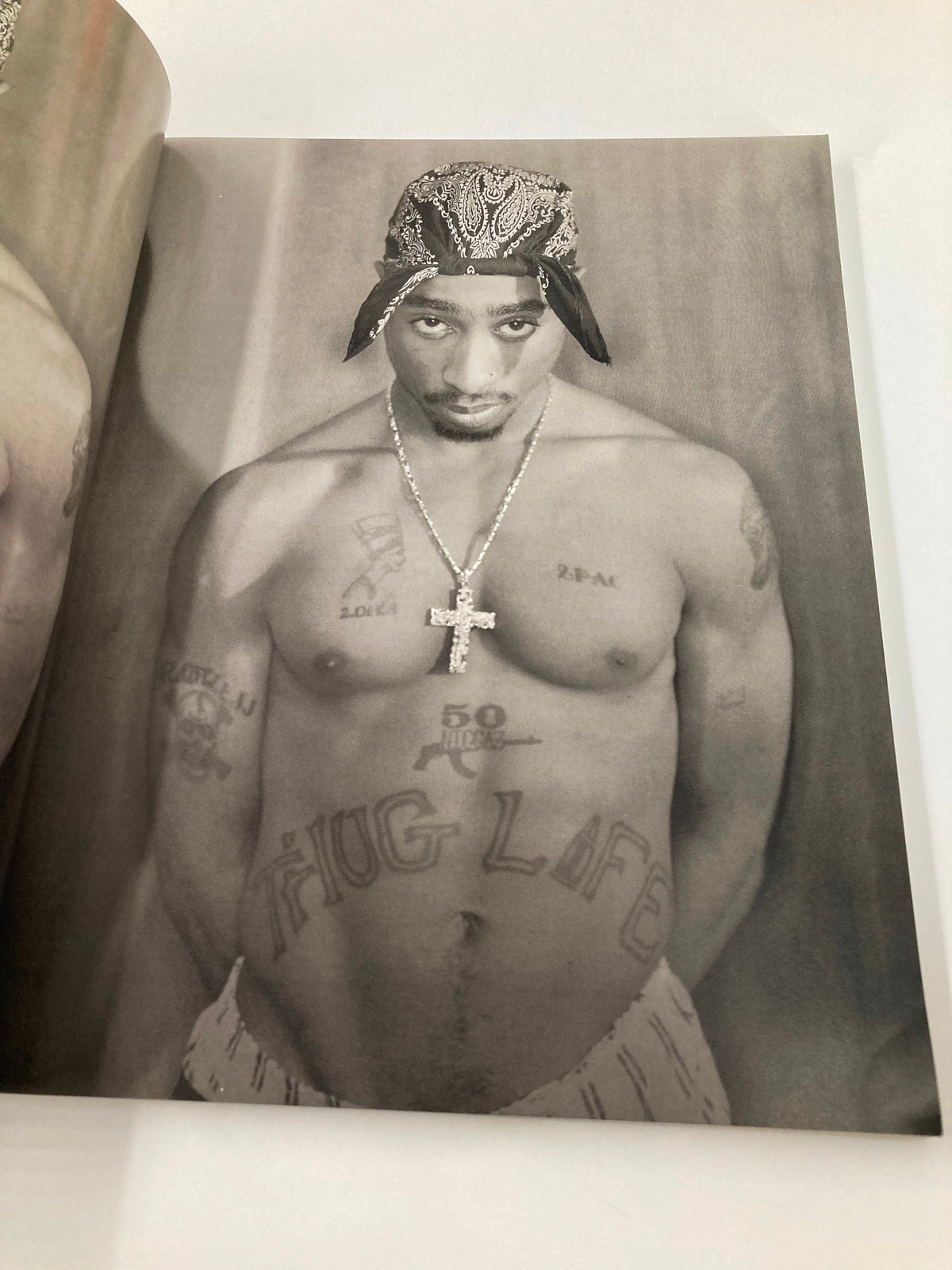 Black and white portrait of Tupac Shakur showcasing his iconic tattoos and style, from 'The New York Times Best Seller Memoir of Tupac Shakur 1971 - 1996', capturing his bold persona.