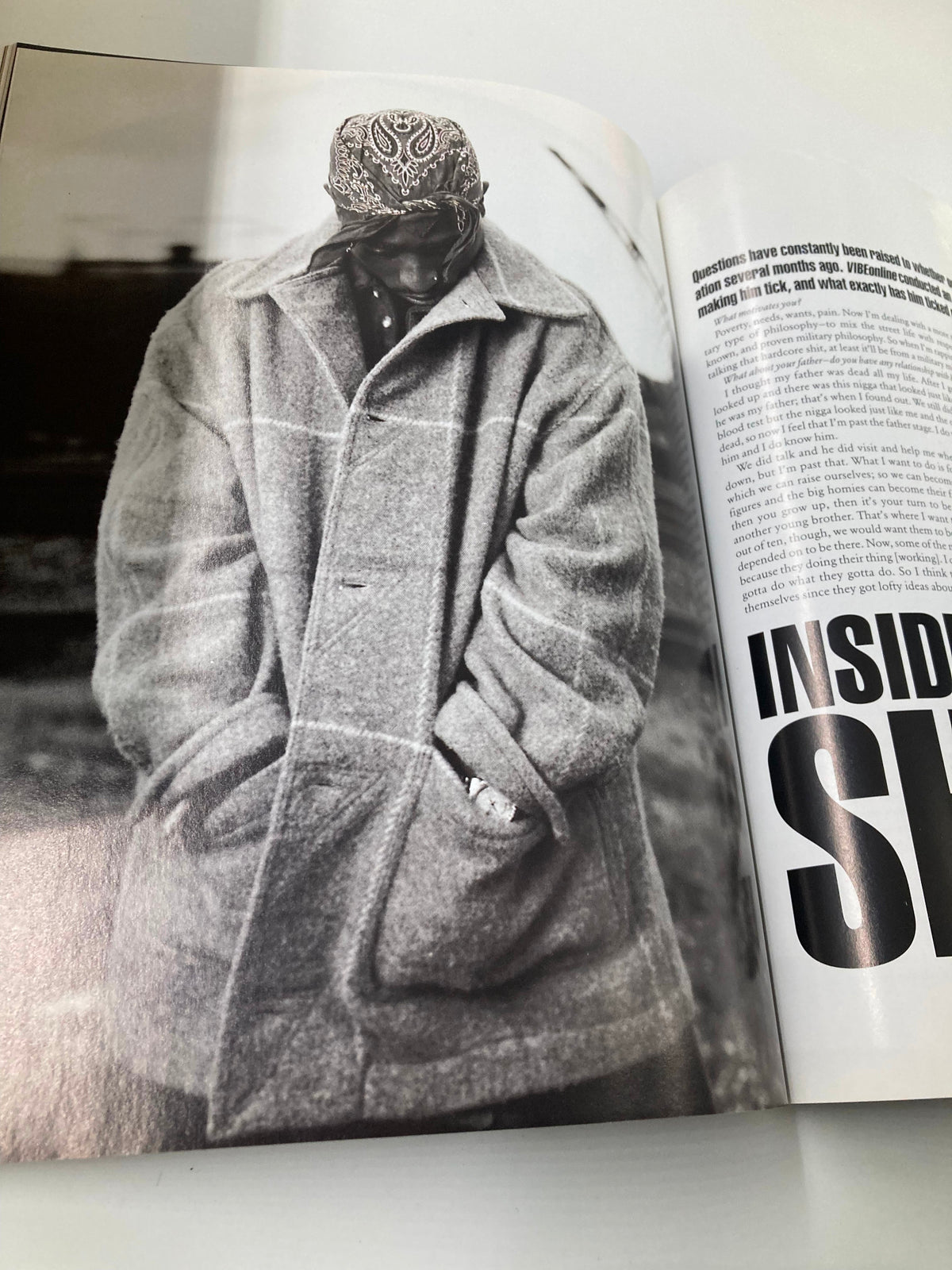 Tupac Shakur Memoir - A contemplative black and white image of Tupac bundled in a large coat, capturing the depth of his character.