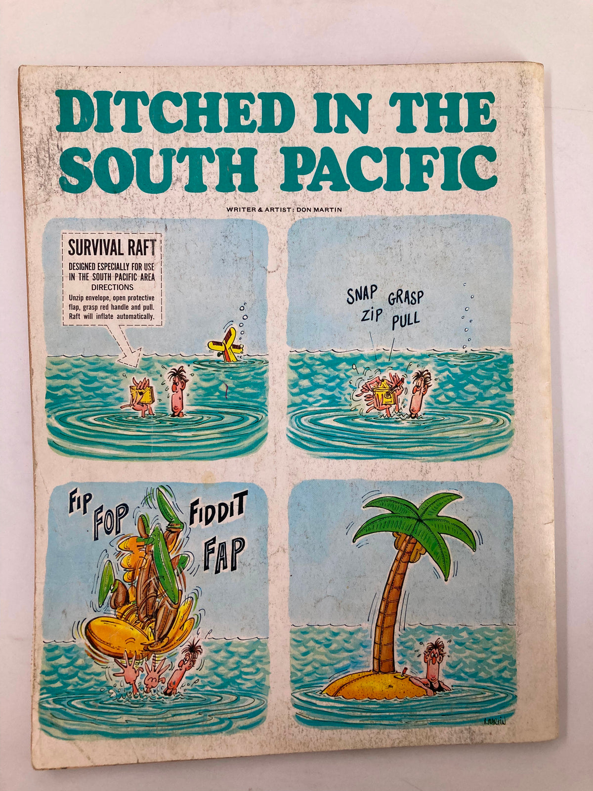 Back cover illustration from Mad Magazine No. 13 featuring the comic strip 'Ditched in the South Pacific' by Don Martin, showcasing humorous characters in a tropical setting with a survival raft and playful dialogue.