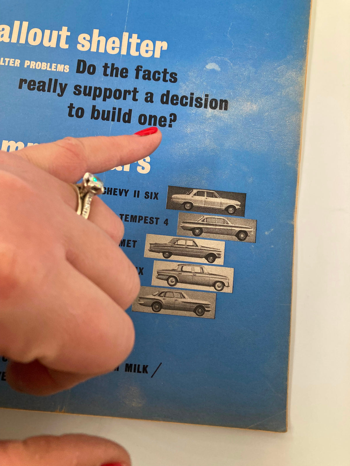Close-up of the cover of the VTG Consumer Reports Magazine January 1962 highlighting the question 'Do the facts really support a decision to build one?' with images of vehicles and a hand pointing to the text.