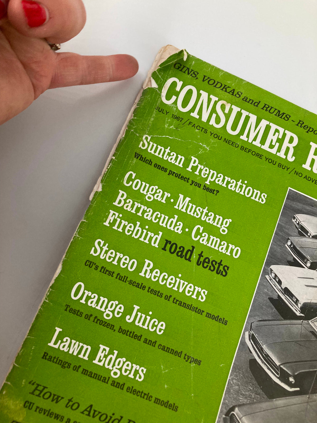 Close-up of the top corner of the VTG Consumer Reports Magazine July 1967 showing details like 'Suntan Preparations' and 'Cougar - Mustang - Barracuda - Camaro - Firebird road tests'.