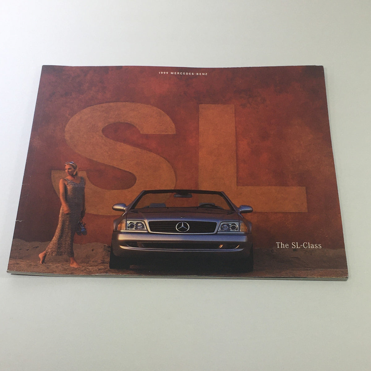 1999 Mercedes-Benz SL-Class Sport Package Dealership Car Auto Brochure Catalog cover featuring a sleek SL-Class car with a model on a sandy background.
