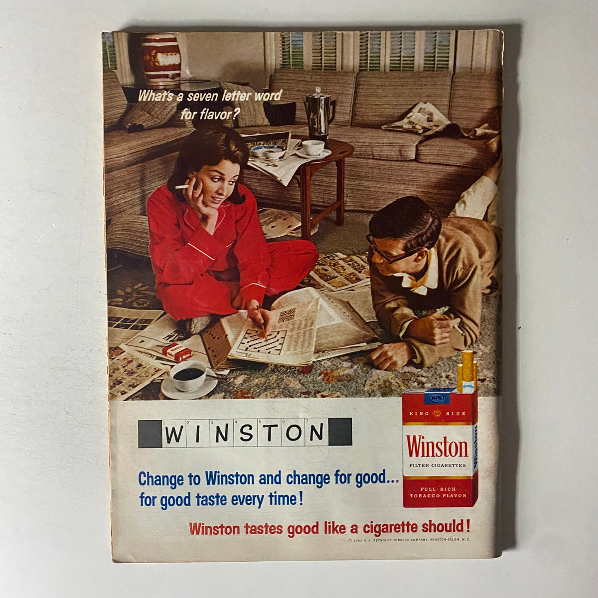 Vintage Winston cigarette advertisement featuring a woman in red pajamas and a man on the floor, promoting the brand with the statement 'Change to Winston and change for good...for good taste every time!'. This ad reflects the 1960s lifestyle.