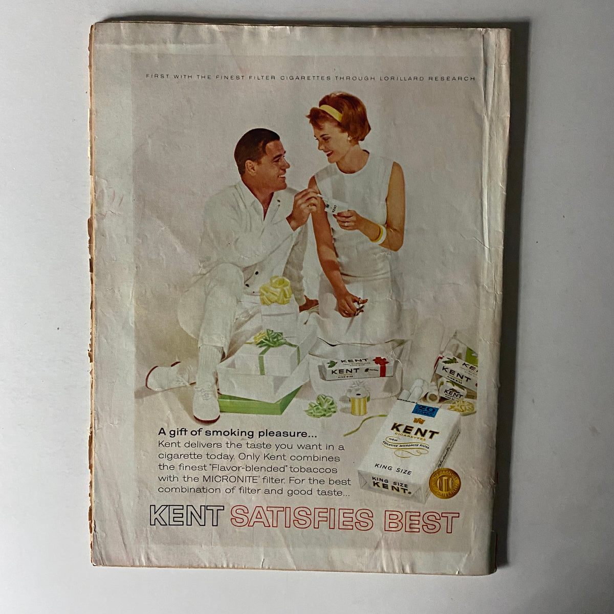Back cover of Time Magazine December 25, 1964, showcasing a vintage advertisement for Kent cigarettes, featuring a couple celebrating with gifts.