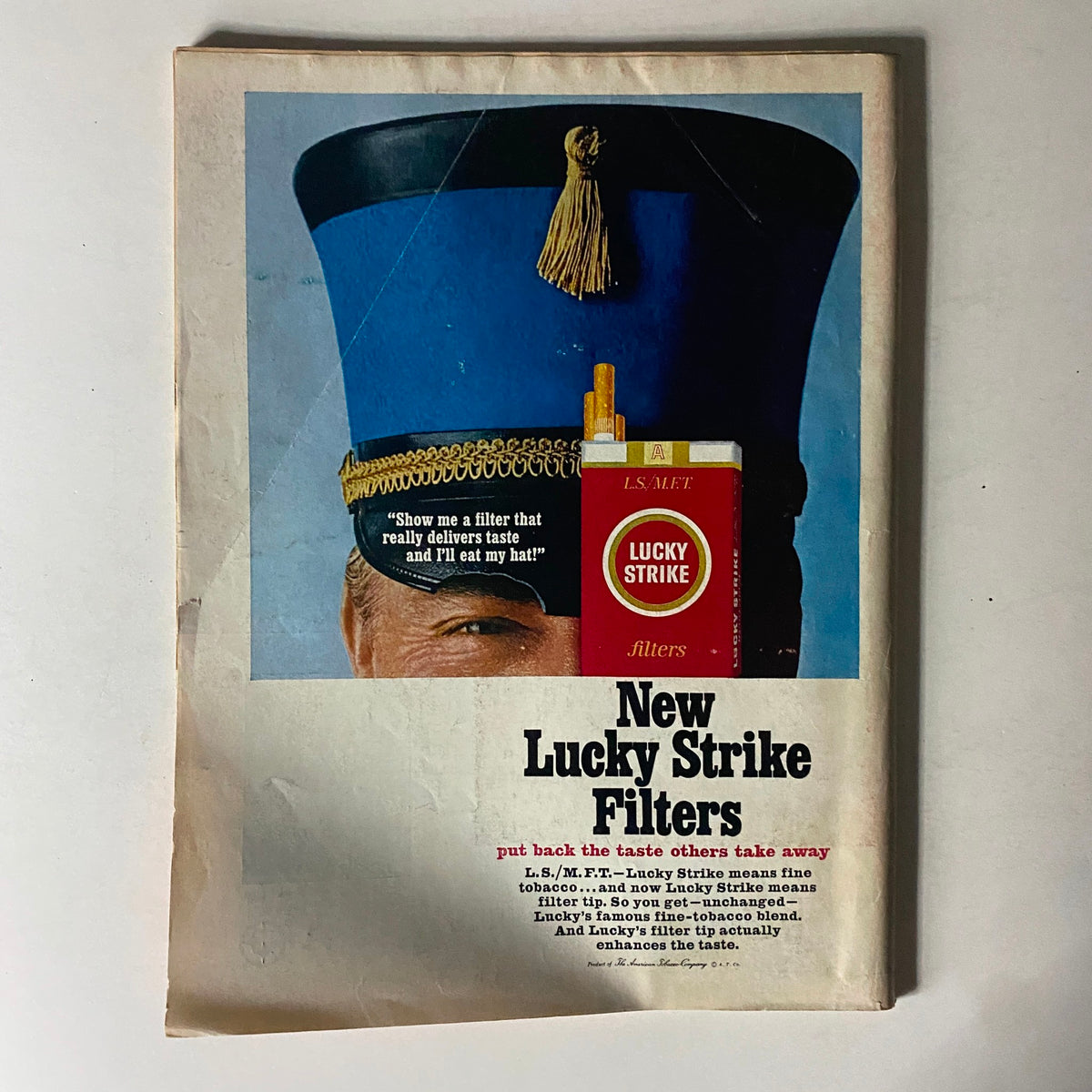 Advertisement for New Lucky Strike Filters, showcasing a man in a blue hat holding a Lucky Strike cigarette pack, promoting the filter's taste benefits.