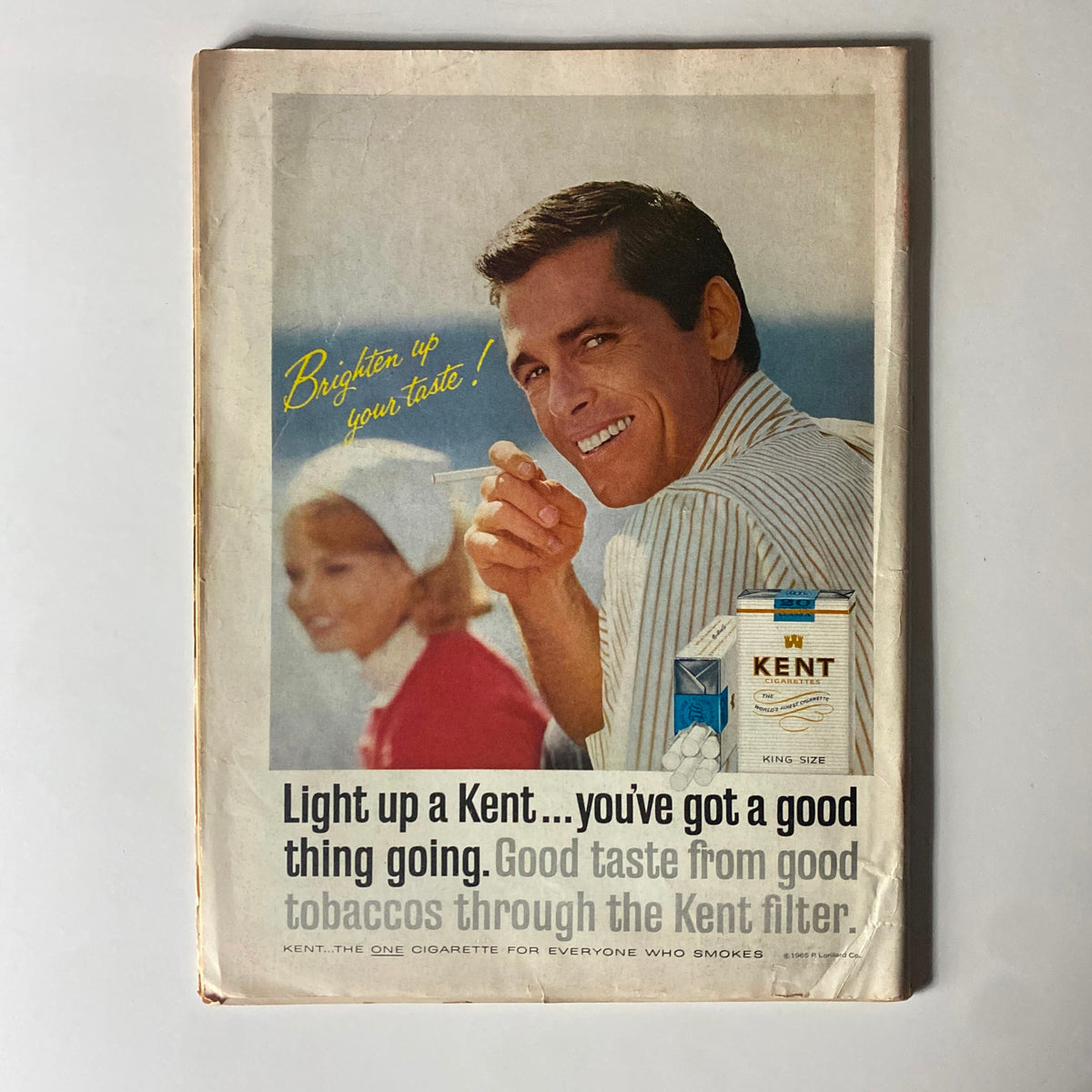 Back cover of a vintage magazine featuring an advertisement for Kent cigarettes, highlighting a promotional message with a smiling man and woman, embodying the cultural aesthetics of the 1960s.