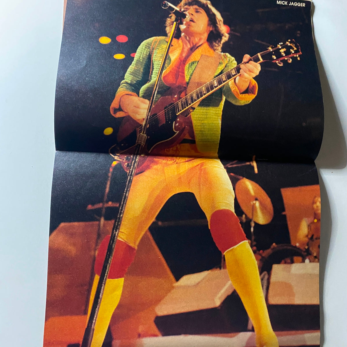 Rock Stars Photo Album No. 7 image of Mick Jagger performing on stage, highlighting his energetic performance style and colorful outfit in the early 1980s.