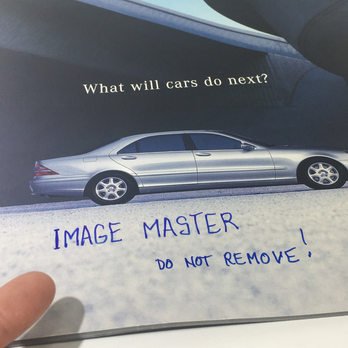 Close-up of the 2001 Mercedes-Benz S-Class Dealership Car Auto Brochure Catalog cover showing a silver Mercedes-Benz S-Class with the caption 'What will cars do next?' and a hand pointing to the note 'IMAGE MASTER DO NOT REMOVE!'