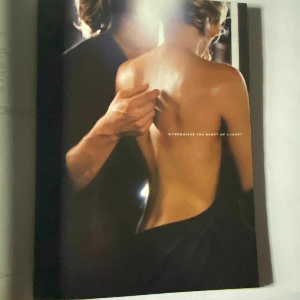 W Magazine October 2002 - A visually striking image featuring a close-up of a woman's bare back being gently touched, promoting the theme 'Introducing the Scent of Luxury', reflecting the essence of fashion in that era.