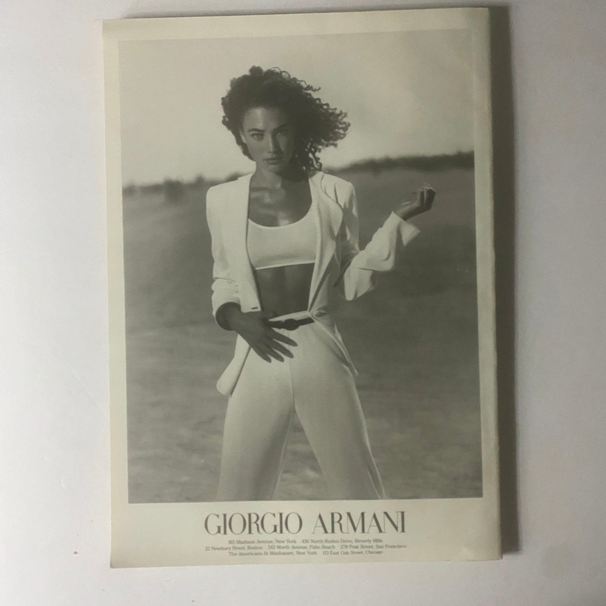 Giorgio Armani fashion advertisement featuring a model in a sleek white suit, embodying 1990s style. This image accompanies the W Magazine June 1996 cover featuring Guinevere Van Seenus, showcasing iconic fashion from the era.