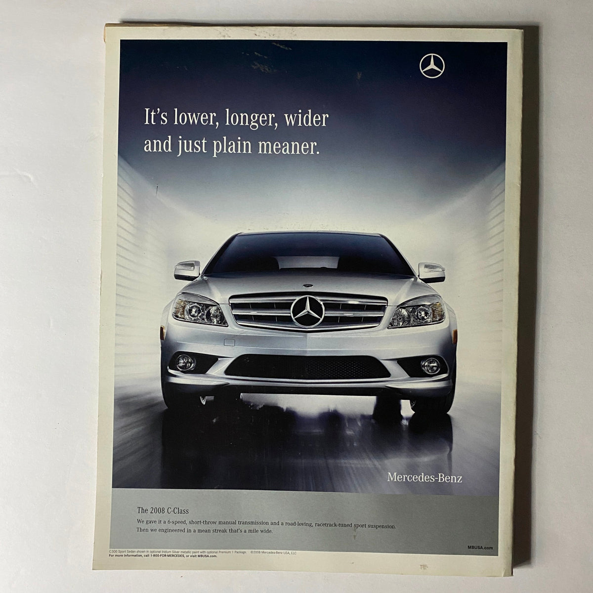 W Magazine June 2008 advertisement showcasing a sleek Mercedes-Benz C Class 2008 model, emphasizing its design with the tagline, "It's lower, longer, wider and just plain meaner."