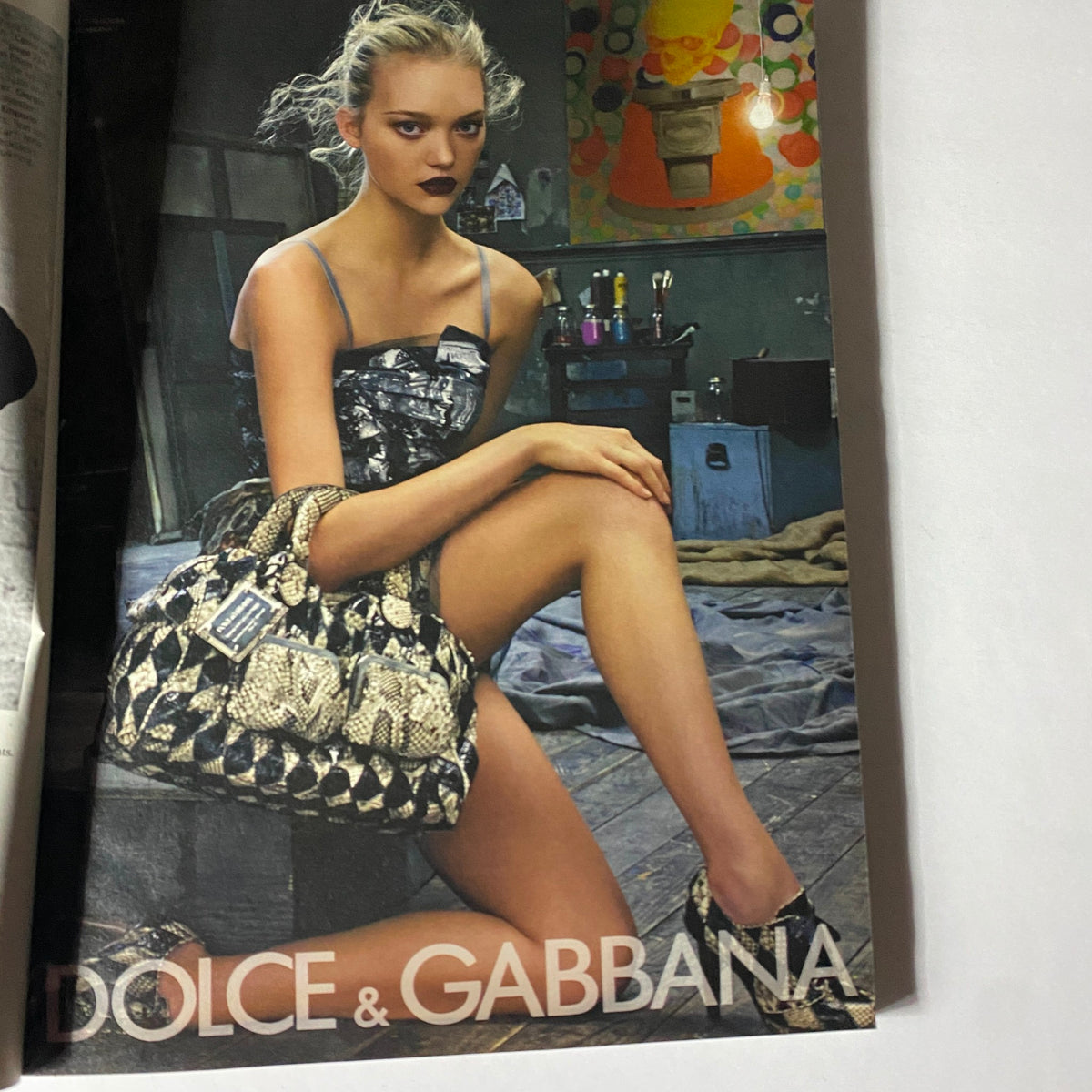 Image from W Magazine April 2008 featuring a model in a Dolce & Gabbana dress showcasing a striking fashion pose and accessories in a gritty studio setting.
