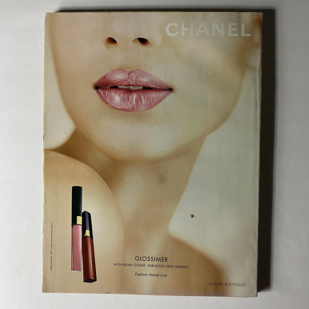 W Magazine April 2004 Gemma Ward Cover showcasing a close-up of lips wearing Chanel Glossimer with sleek makeup products, emphasizing beauty trends from the early 2000s.