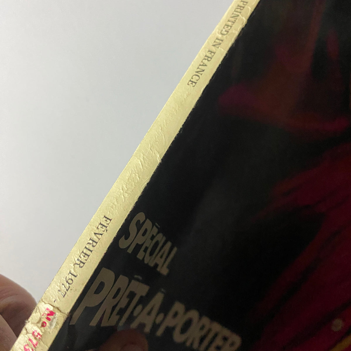 Close-up of the spine of Vogue Paris Magazine February 1977, highlighting the golden embossed text and printed details about its special prêt-à-porter edition.