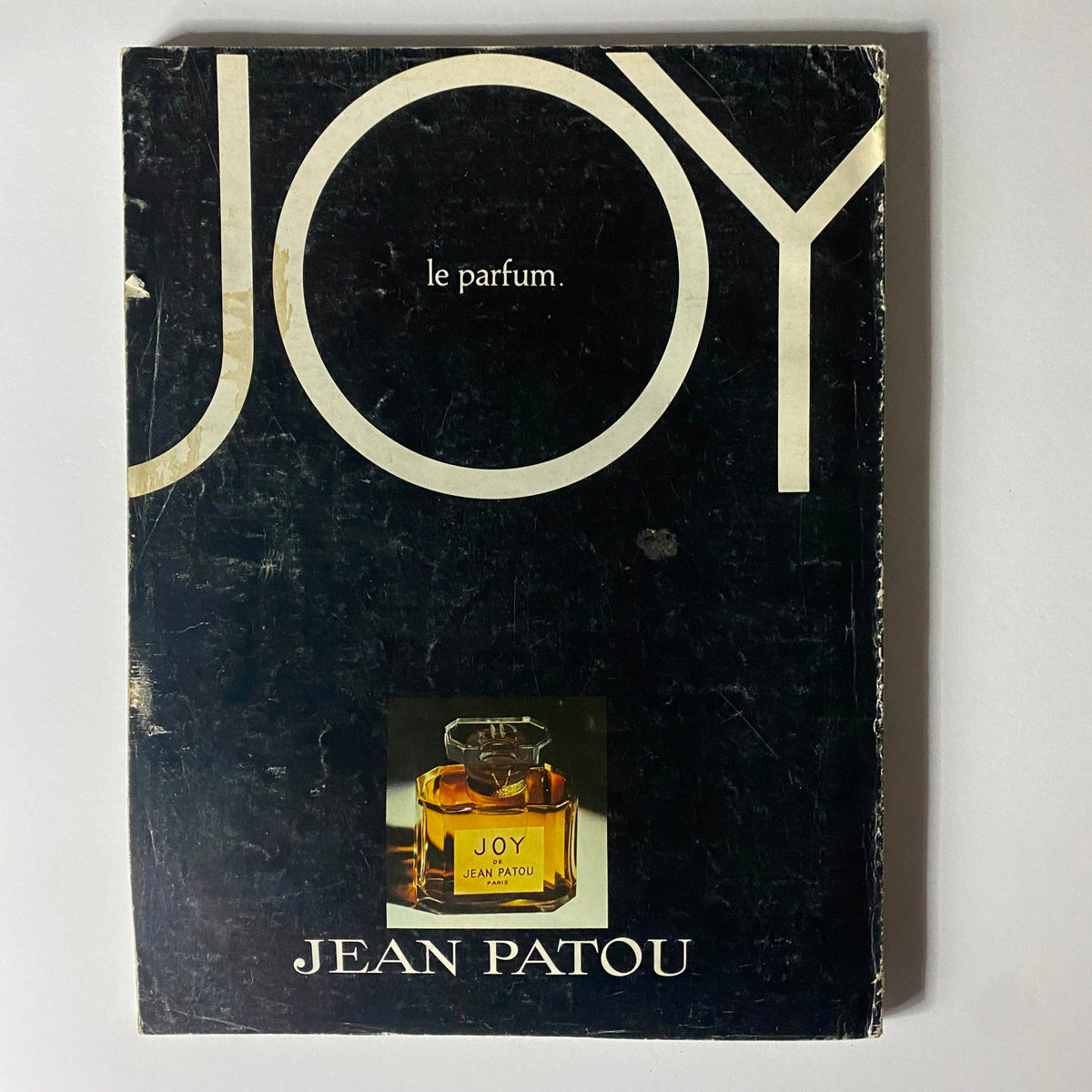 Cover image of Jean Patou's perfume advertisement, showcasing the luxurious 'Joy' fragrance bottle, highlighting vintage perfume marketing from the 1970s. Vogue Paris Magazine February 1977 Marcie Hunt by Guy Bourdin Cover No Label.
