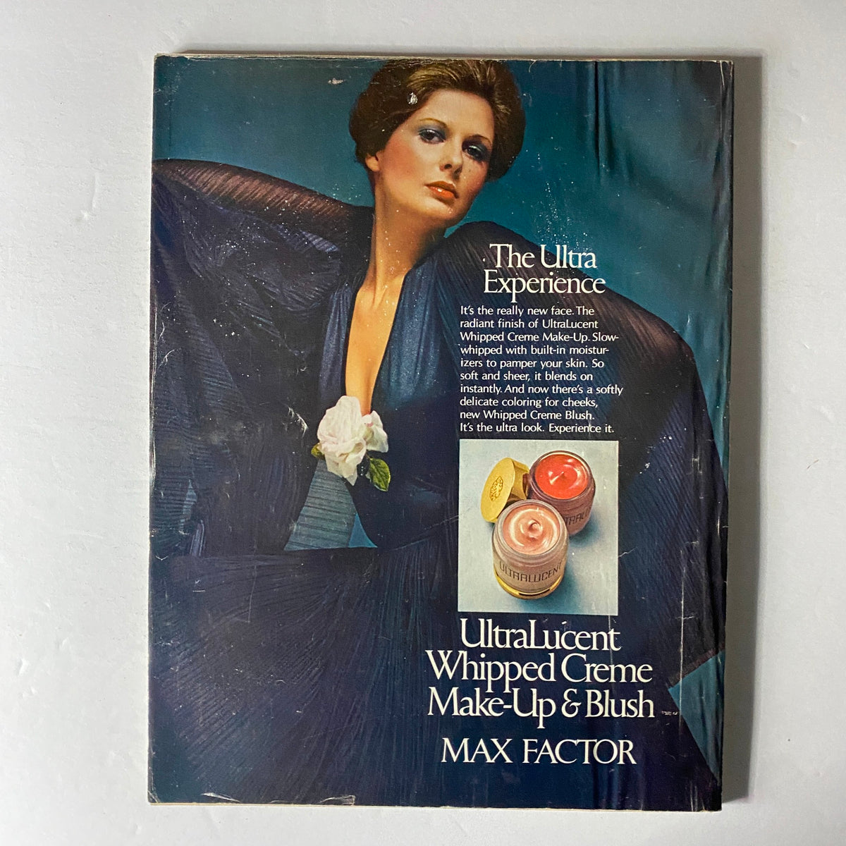 Cover of the Max Factor advertisement from the 1970s promoting UltraLucent Whipped Creme Make-Up and Blush, featuring a model showcasing the 'Ultra Experience', linked to Vogue Magazine April 1974.