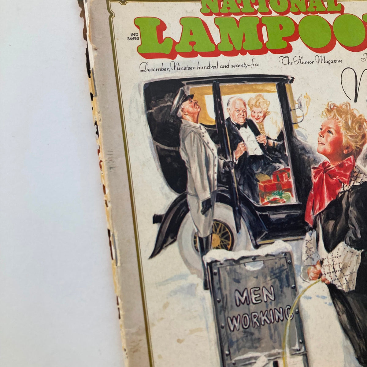 Close-up of the cover of Vintage National Lampoon Magazine December 1975, 'God Is Money', displaying a child in a fancy outfit and another man in a vintage car.