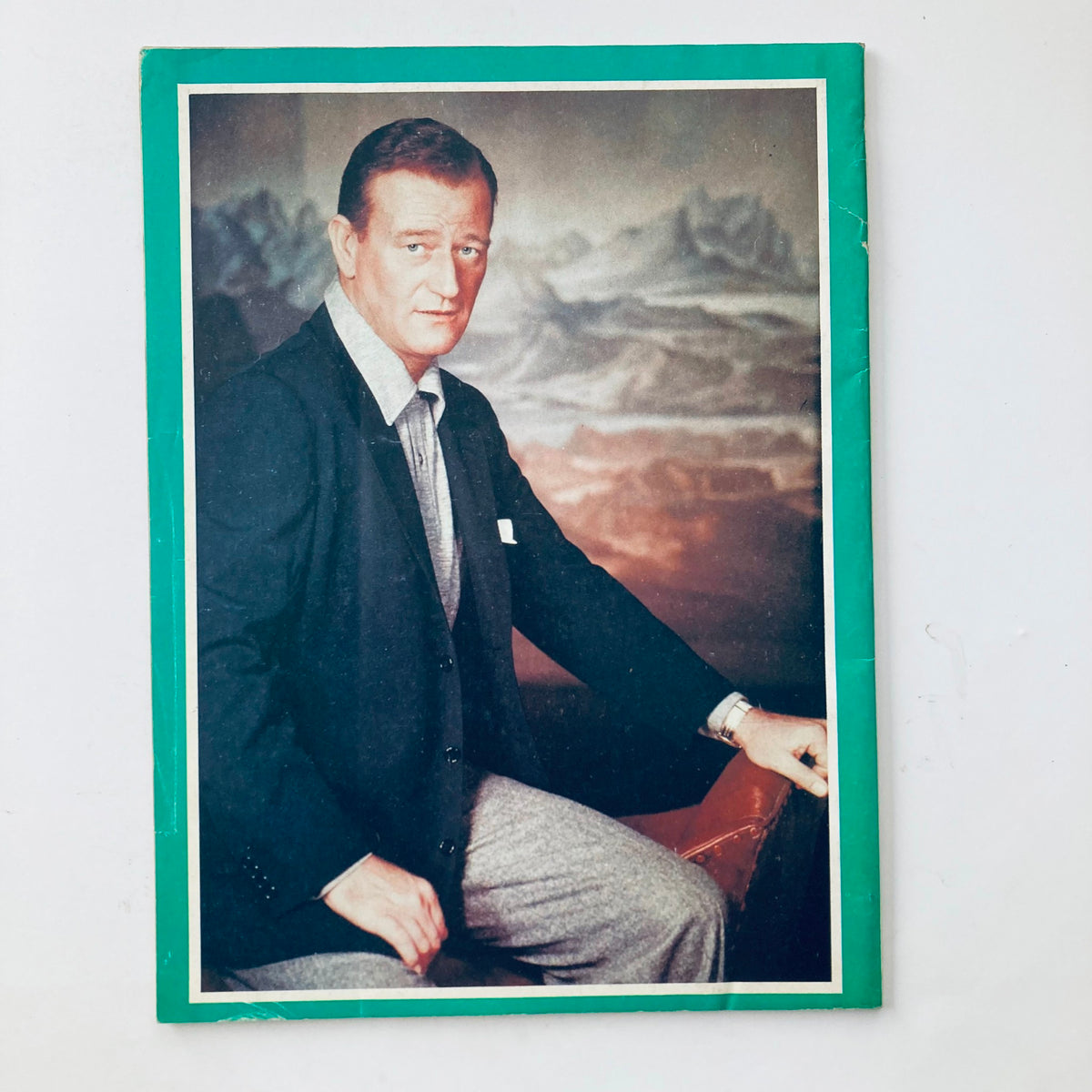 Portrait of John Wayne featured in the VTG 1979 John Wayne and The Great Cowboy Heroes publication, showcasing the iconic actor in a classic suit against a scenic backdrop.
