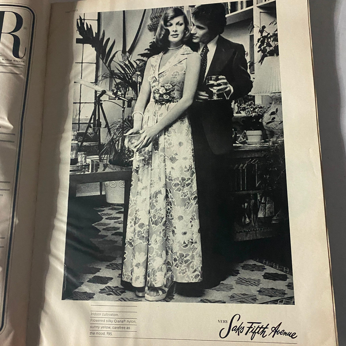 Vintage black and white advertisement featuring a model in a floral gown from the Harper's Bazaar Magazine, May 1973, showcasing early 1970s fashion elegance.
