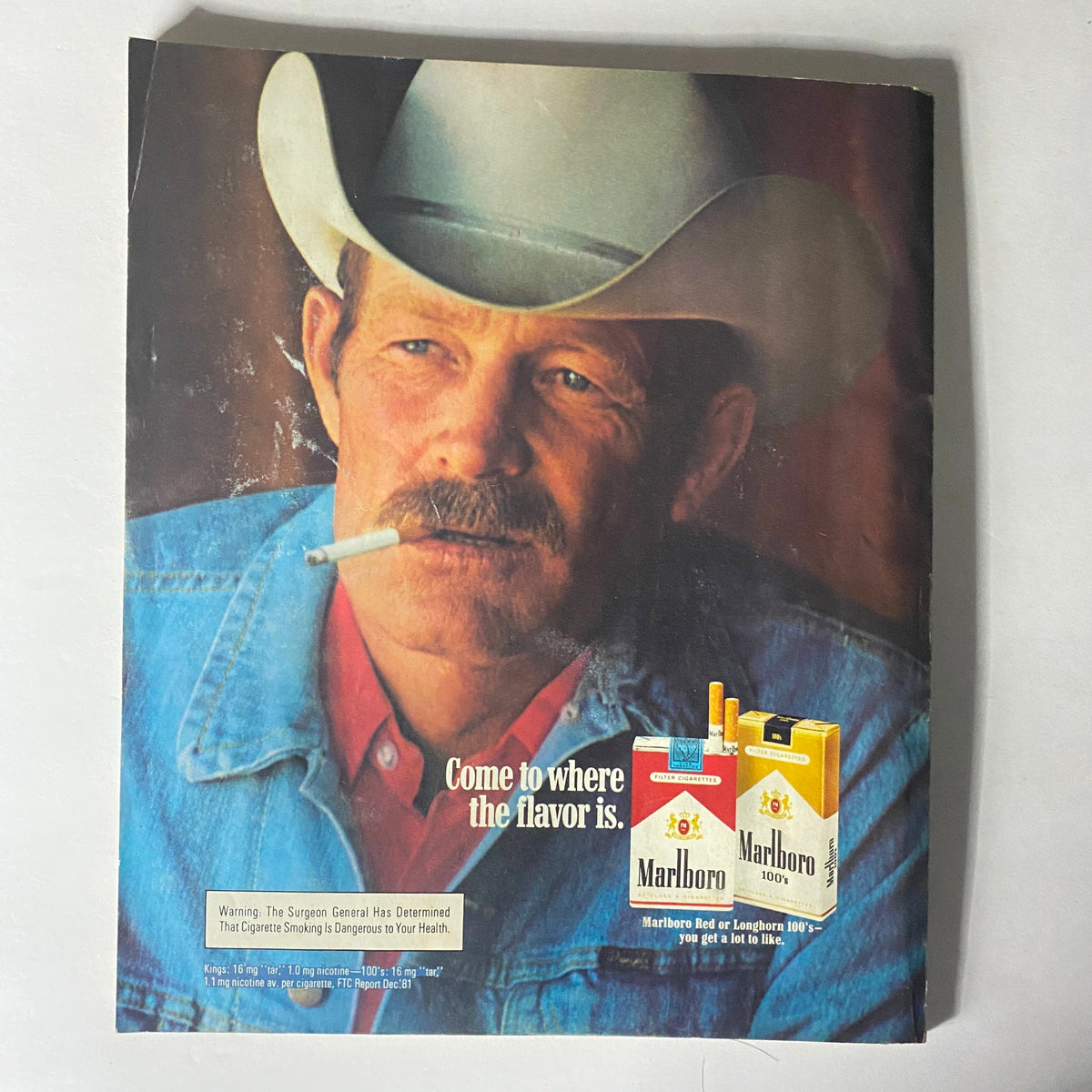 Harper's Bazaar Magazine July 1982 advertisement for Marlboro cigarettes, depicting a rugged man in a cowboy hat, emphasizing classic Americana style.