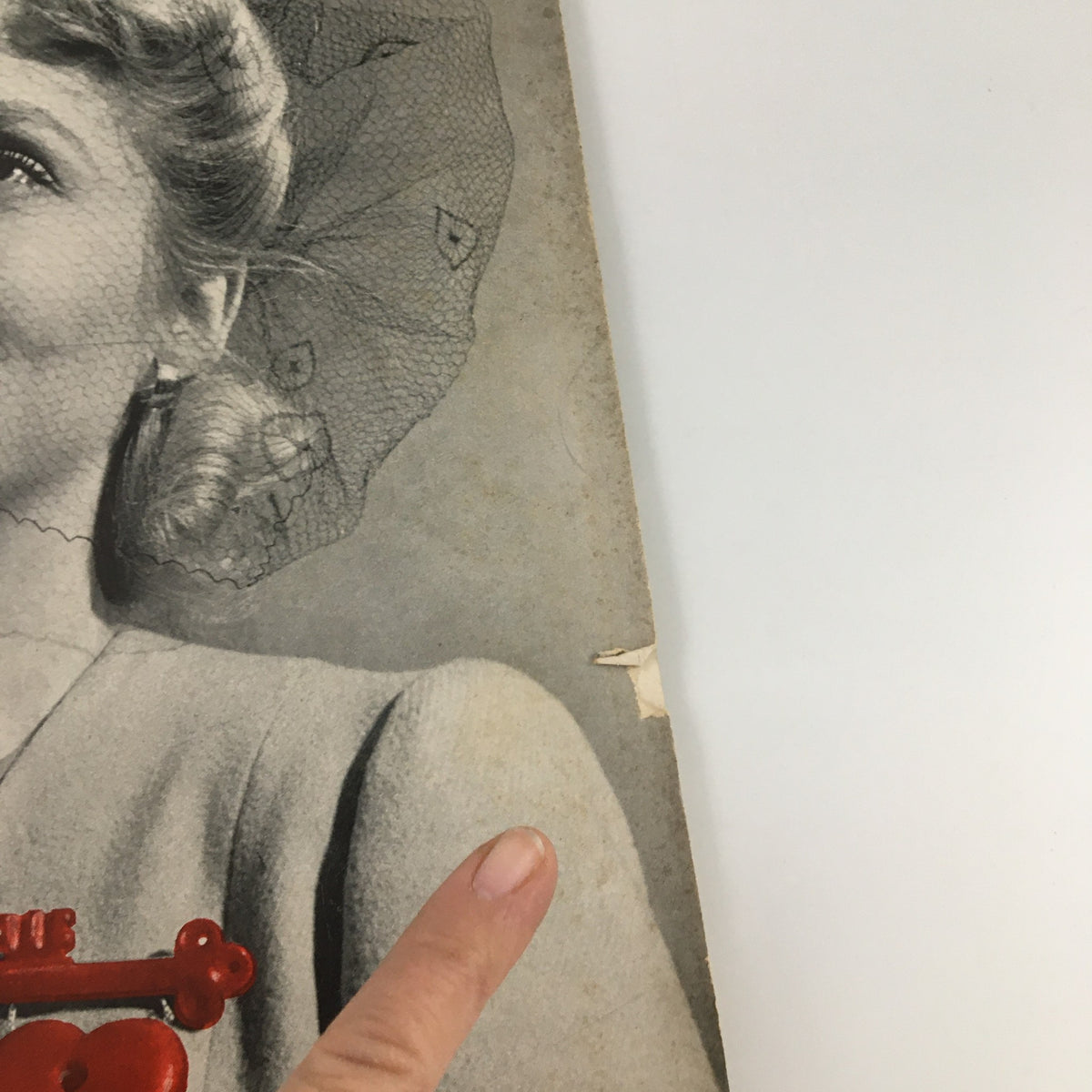 Close-up of the cover of VTG Life Magazine from April 28, 1941, highlighting the details of the smiling woman, her hat, and heart-shaped pin, along with edge wear typical of vintage publications.