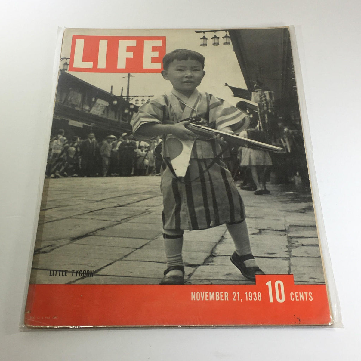 Vintage Life Magazine cover from November 21, 1938 titled 'Little Tycoon', featuring a young child in traditional attire holding a toy trumpet, set against a bustling street scene.