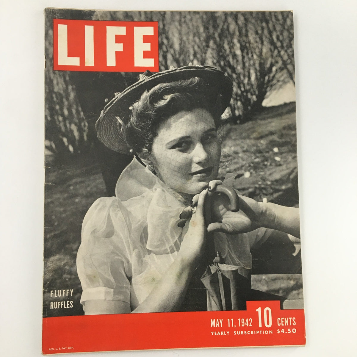 Cover of Life Magazine from May 11, 1942 featuring the 'Fluffy Ruffles' theme. The magazine showcases a woman in vintage fashion, adorned in a whimsical hat and veil, evoking the elegance of the early 1940s.