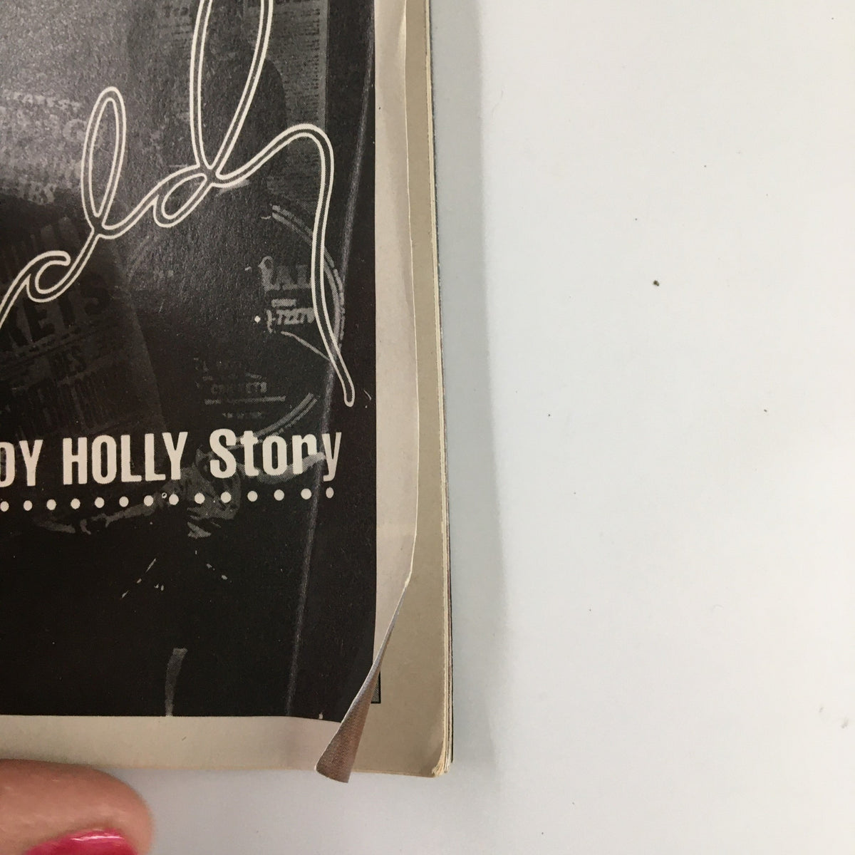 Detail of the edge of the 1991 Playbill for The Buddy Holly Story, highlighting the cover texture and minor wear.