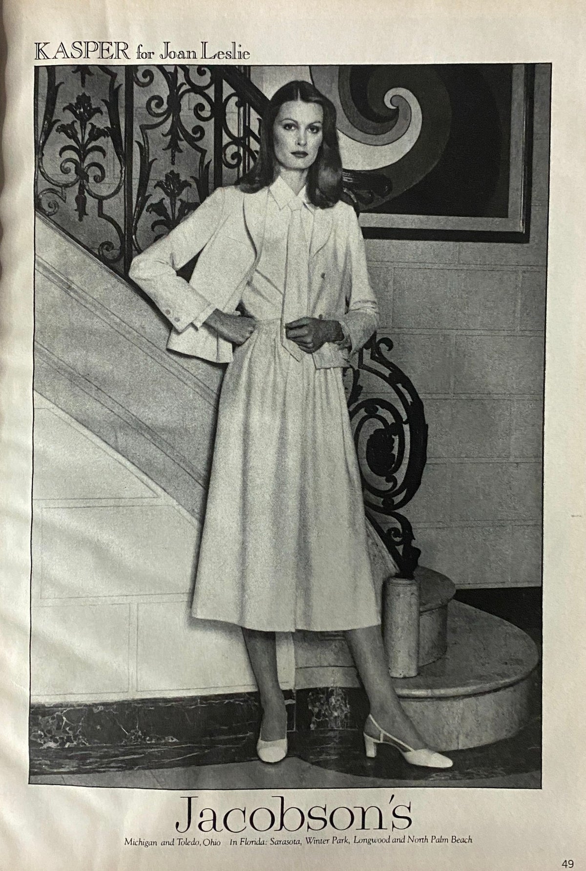 Interior page from Vogue Magazine February 1978, featuring a stylish model in a white outfit by KASPER for Joan Leslie, set against an elegant staircase backdrop, illustrating classic fashion from the era.