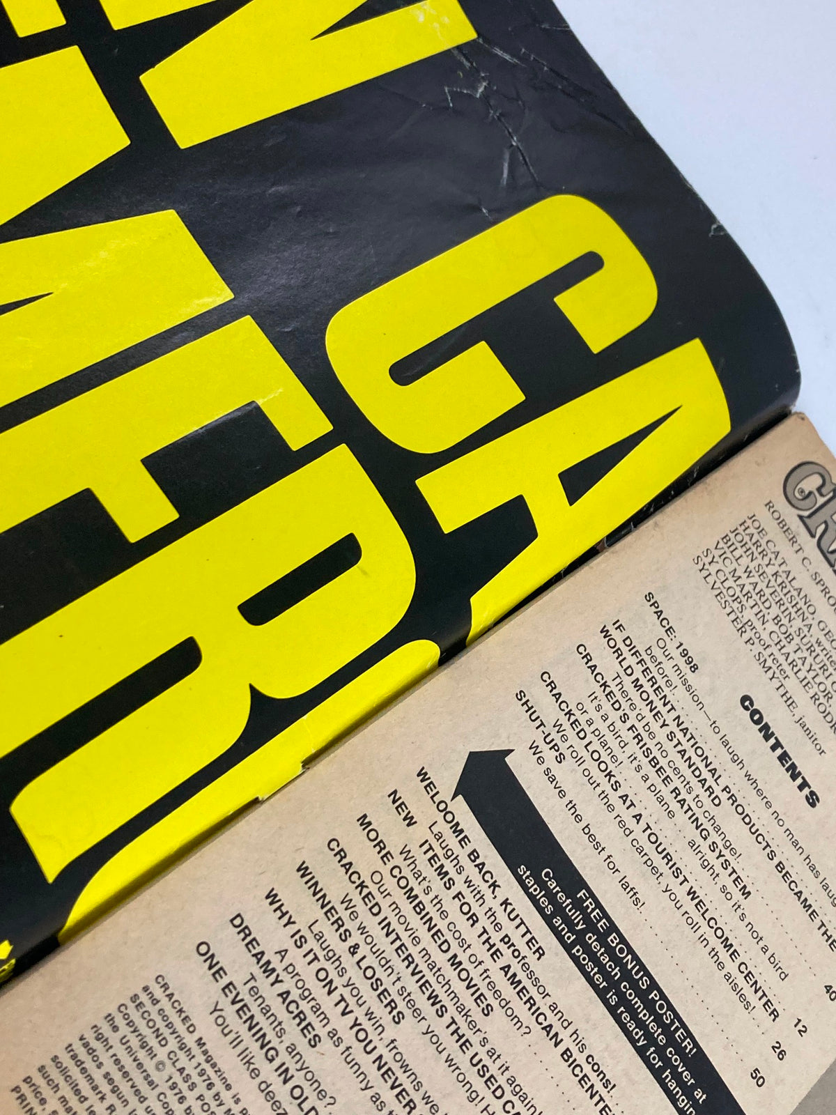 Close-up view of the cover of the VTG Cracked Humor Magazine, July 1976, Issue #133, showcasing bold yellow lettering and humorous illustrations. The image captures the retro design typical of 1970s magazines.