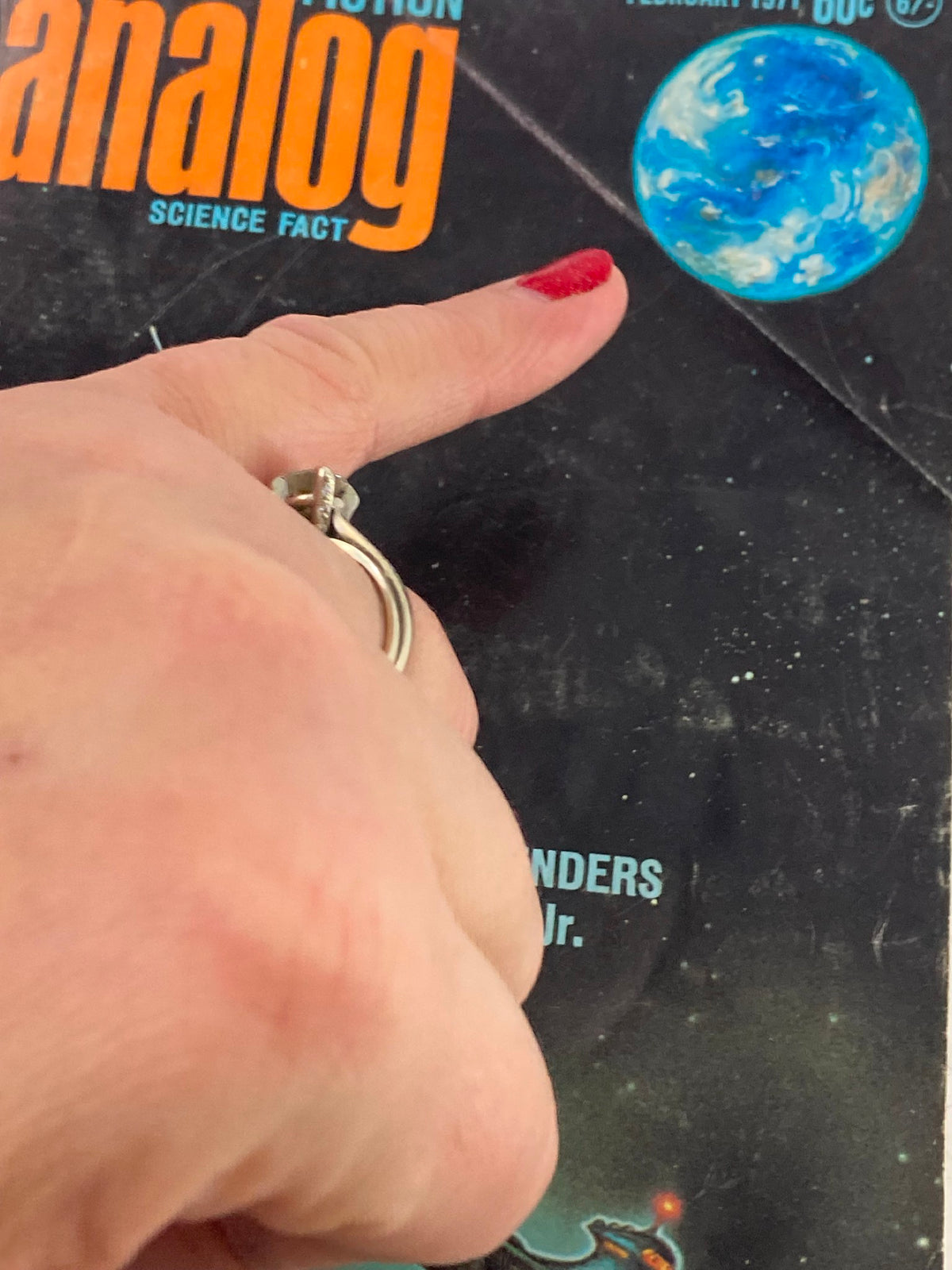 A close-up view of the cover of the February 1971 issue of Analog Science Fiction / Science Fact, highlighting the title 'The World Menders' and showcasing a planet with a finger pointing at it.