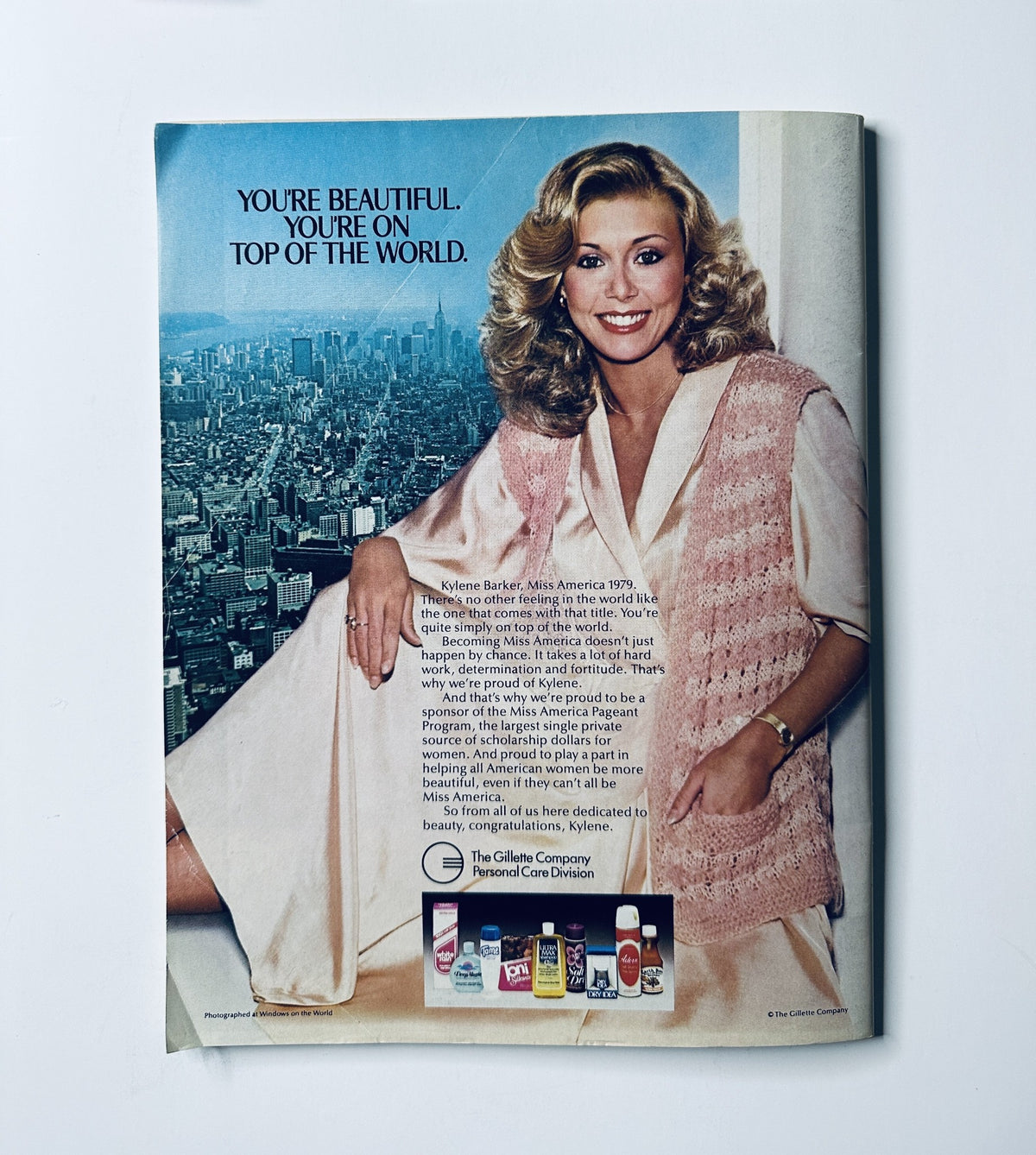 Promotional image of Kylene Barker, Miss America 1979, sitting in a stylish pink vest, promoting beauty products in the 1979 Miss America Pageant Magazine Program, emphasizing self-confidence and beauty.