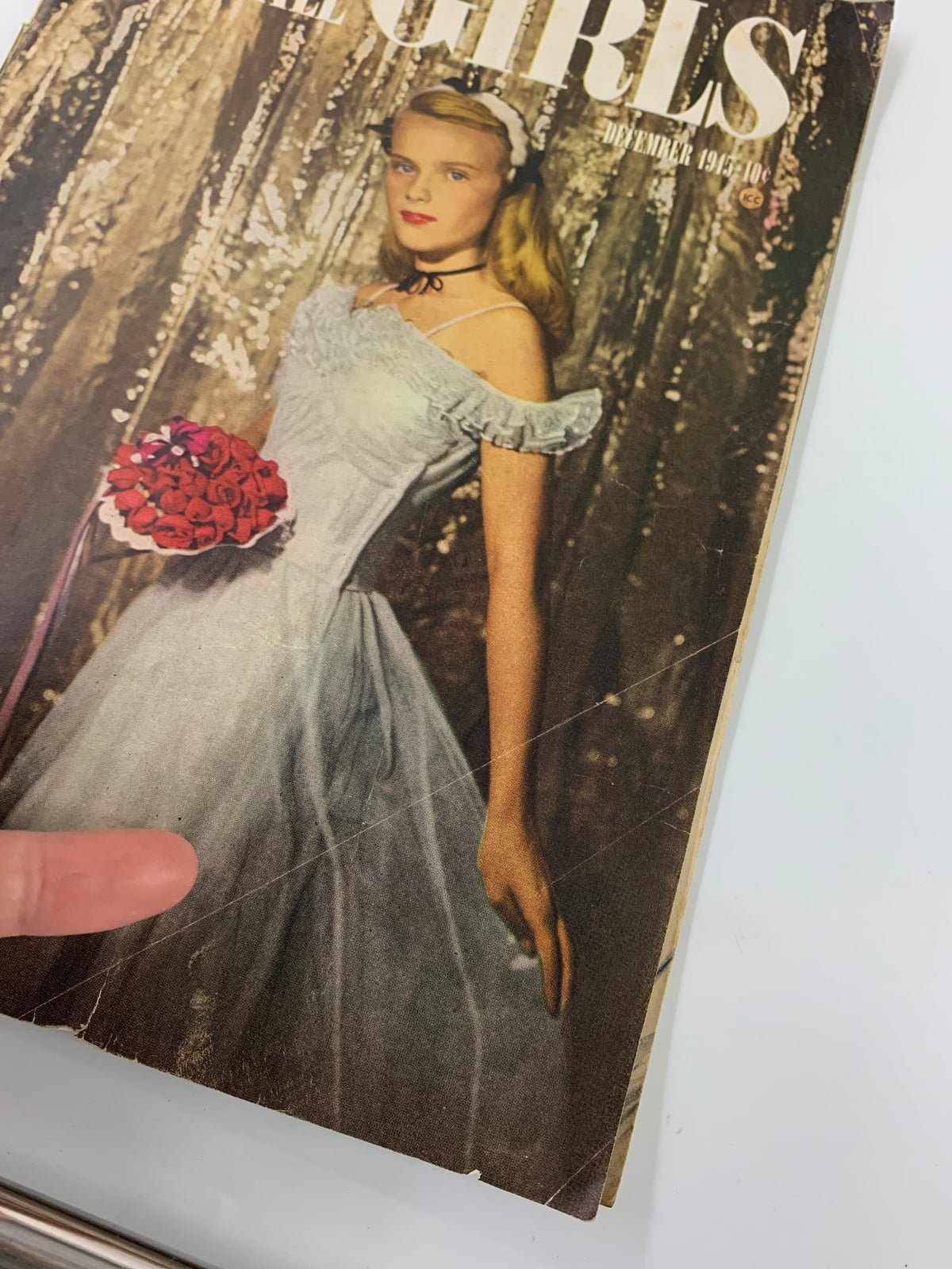 Close-up view of the VTG Calling All Girls Magazine December 1945 cover highlighting a young woman in a blue dress with roses, showcasing vintage fashion and charm.