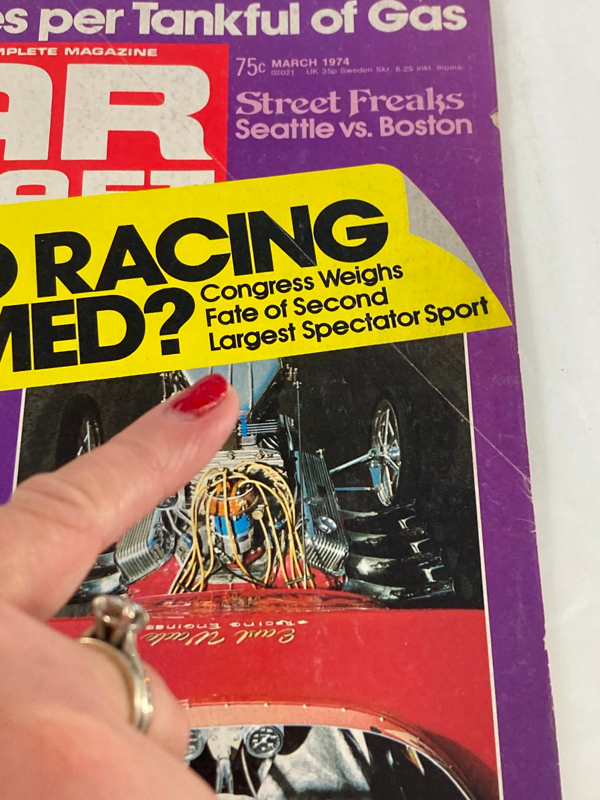 Close-up of the VTG Car Craft Magazine March 1974 cover showing details of the title and a hand pointing at the feature on the fate of auto racing.