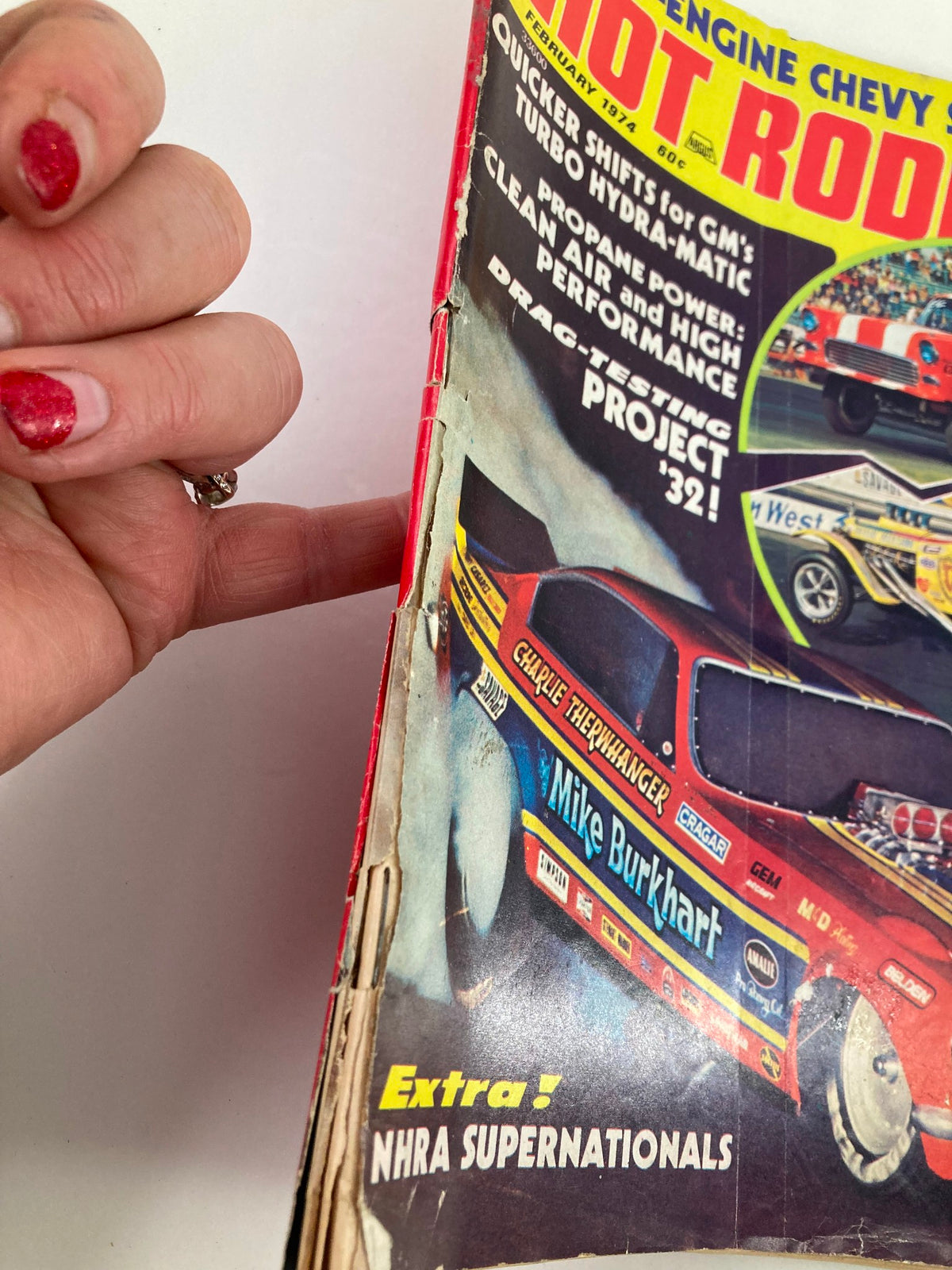 Side view of VTG Hot Rodding Magazine February 1974 Vol 13 #2 showcasing the damage on the cover, emphasizing the vintage character of the magazine.