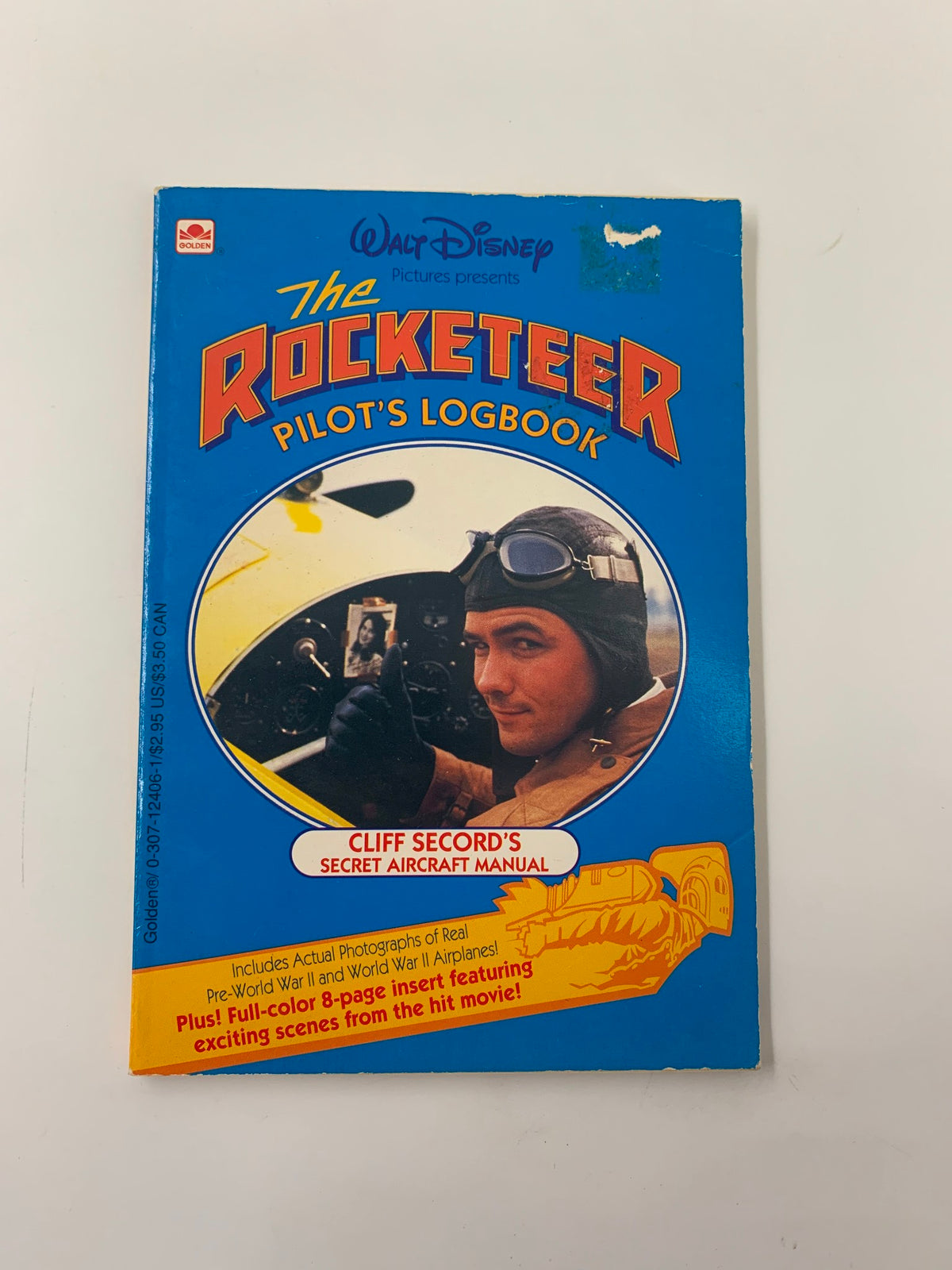 Cover of the Walt Disney The Rocketeer Pilot's Logbook Cliff Secord's Secret Aircraft Manual, featuring a vintage design and an image of Cliff Secord in pilot gear.