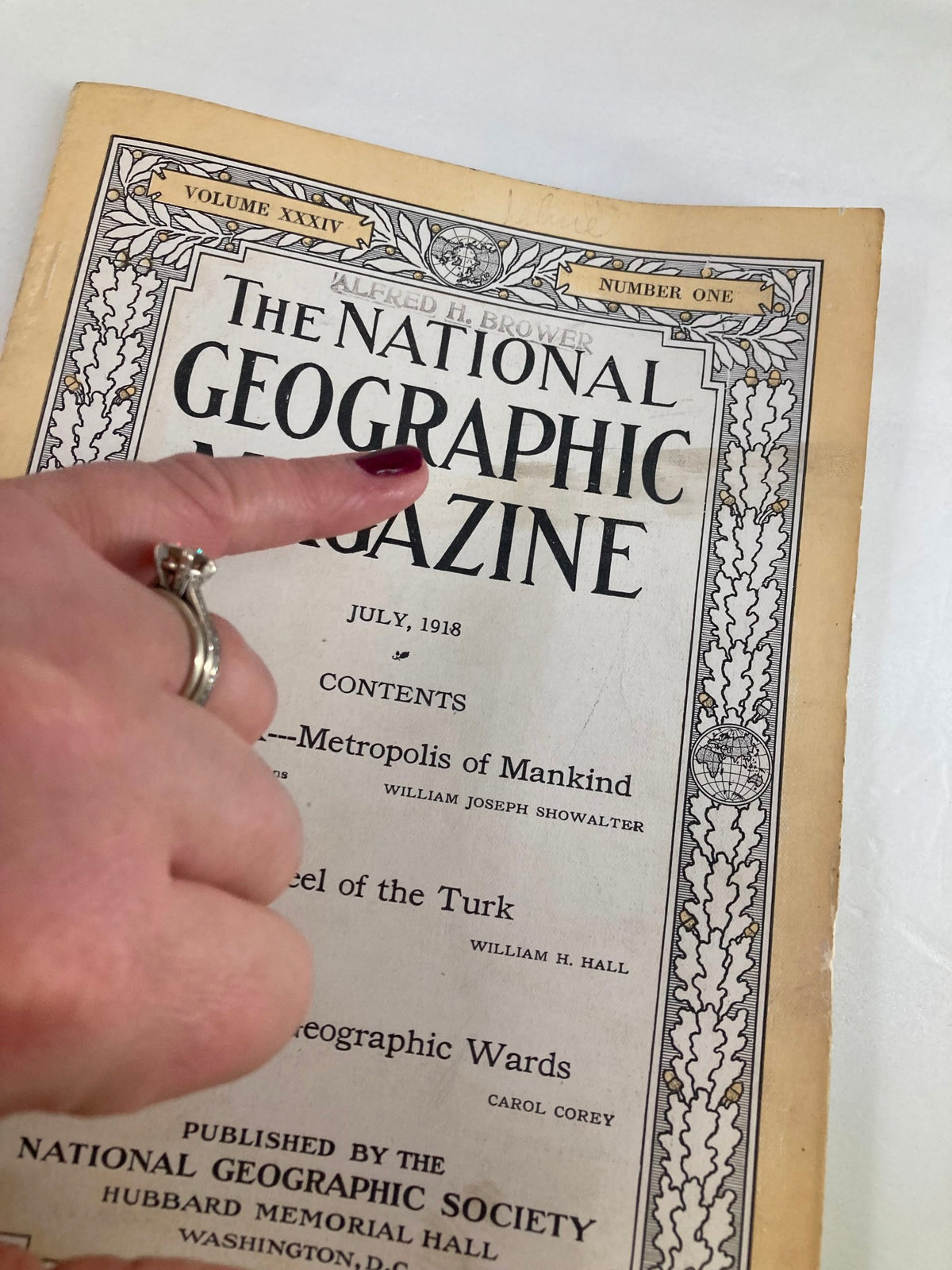 Close-up view of the cover of VTG The National Geographic Magazine July 1918 with a hand pointing at the title and contents details.