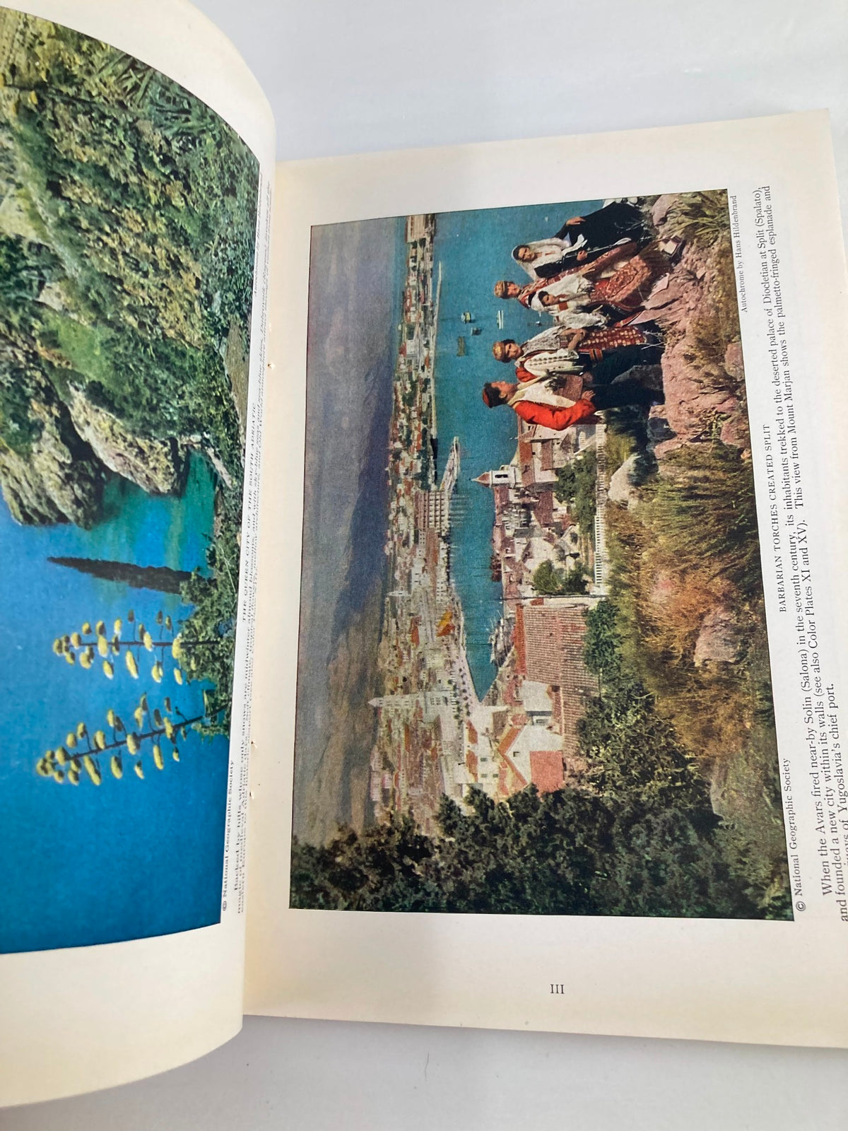 Colorful illustration from The National Geographic Magazine January 1928 depicting a scenic view of a coastal city with boats and hills, highlighting the artistic style of the era.