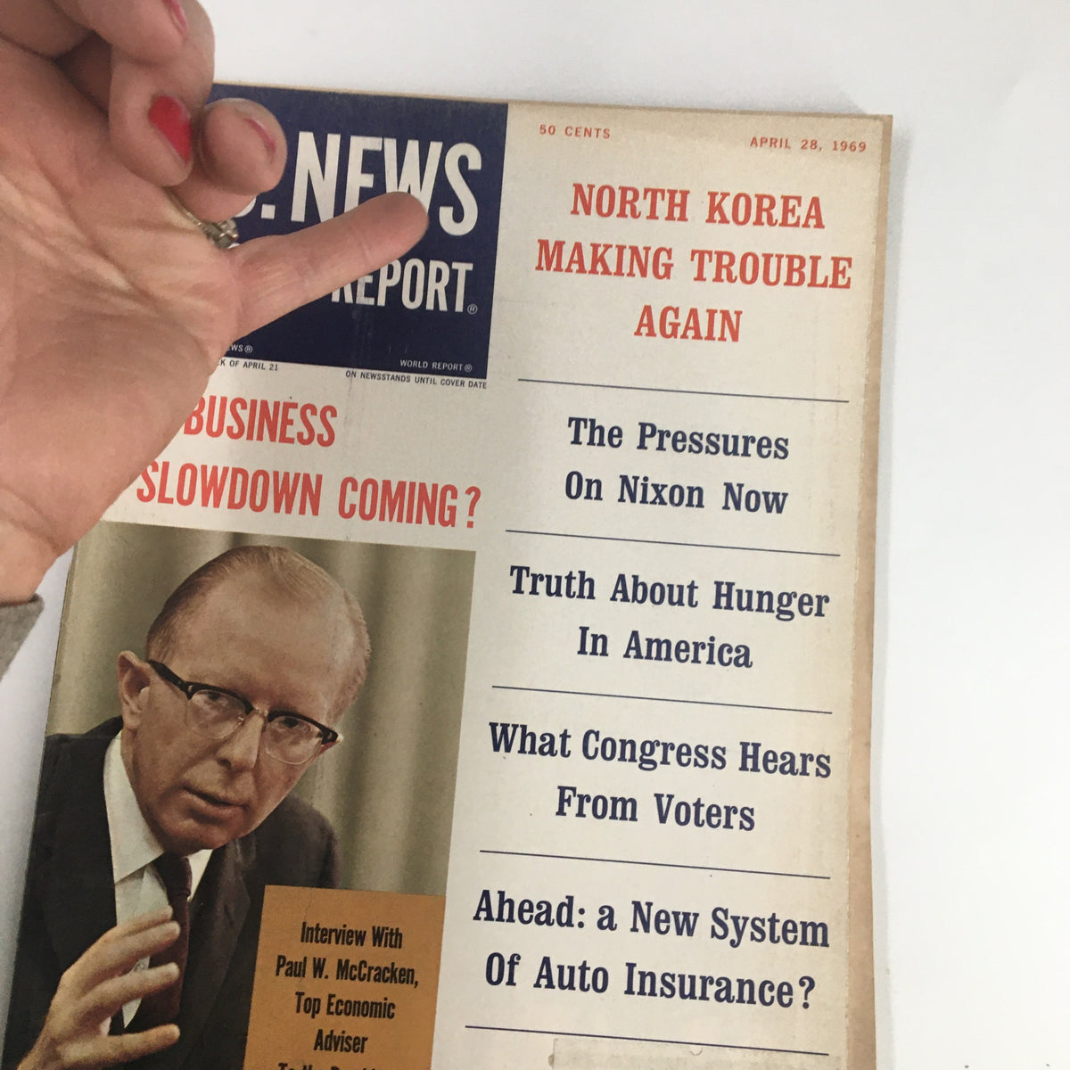 Hand holding US News & World Report Magazine April 28 1969, highlighting the cover and its featured stories, including an interview with Paul W. McCracken.