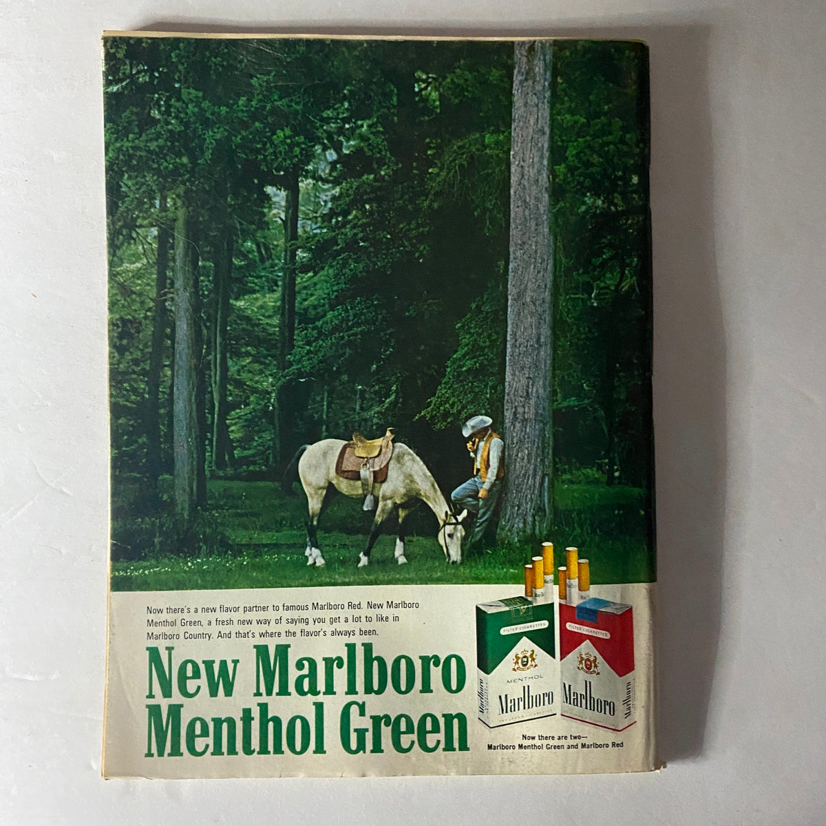 Advertisement for New Marlboro Menthol Green featured in a vintage magazine, showcasing a scene in nature with a horse and man, highlighting its promotional campaign.