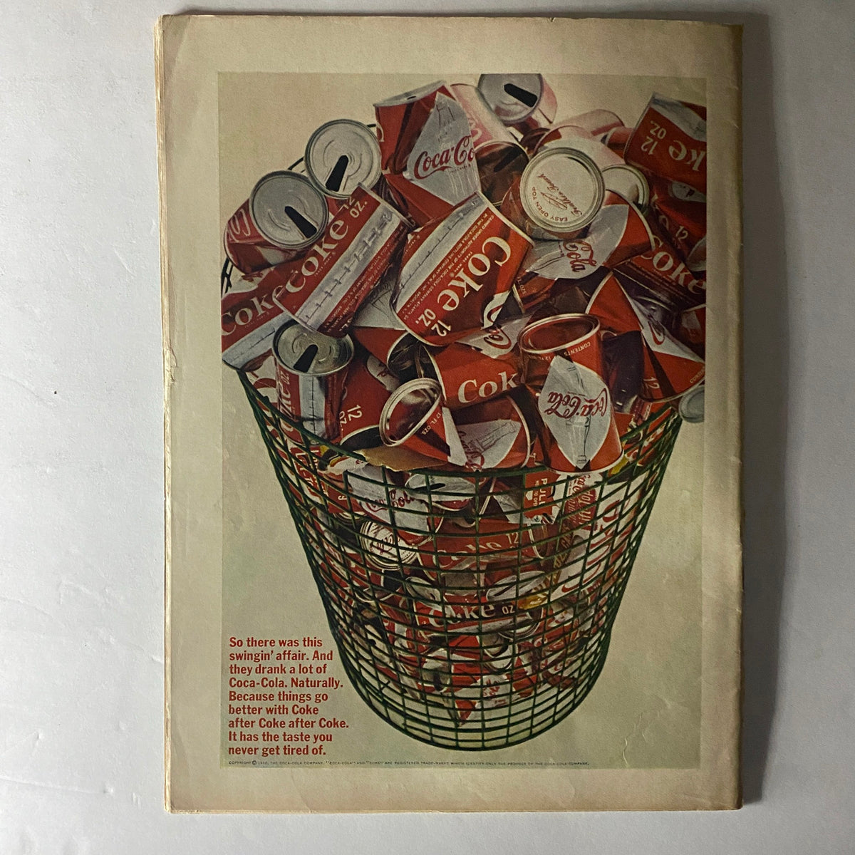 Back cover of American Girl Magazine June 1966 displaying an artistic image of a wire basket filled with Coca-Cola cans, promoting the beverage.
