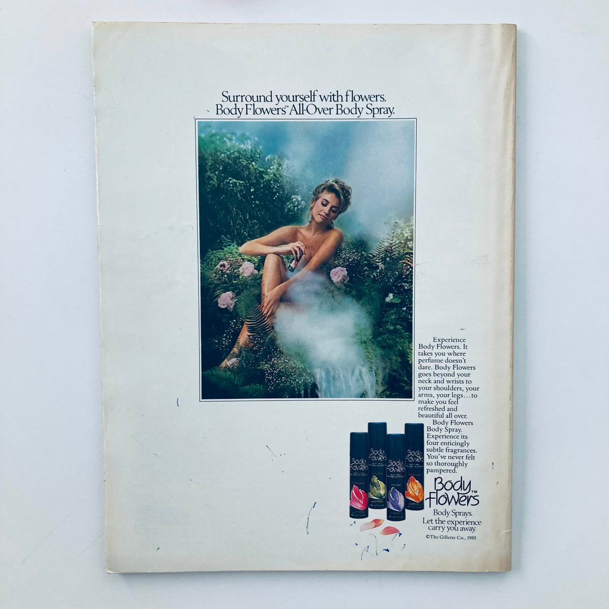 Back cover of VTG Seventeen Magazine February 1985 advertising Body Flowers All-Over Body Spray, featuring a serene image of a model surrounded by flowers.