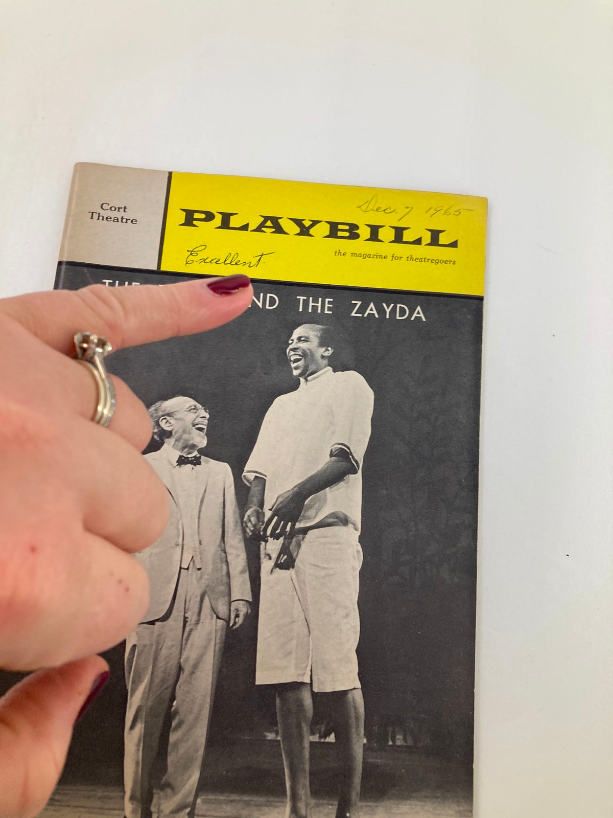 Close-up of the 1965 Playbill from Cort Theatre for The Zulu and The Zayda with a hand pointing to the cover, highlighting its vintage condition.