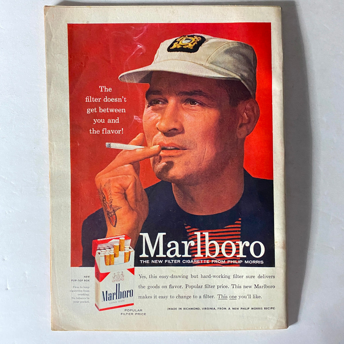 Vintage advertisement for Marlboro cigarettes featuring a man in a cap, emphasizing the flavor of the cigarettes.