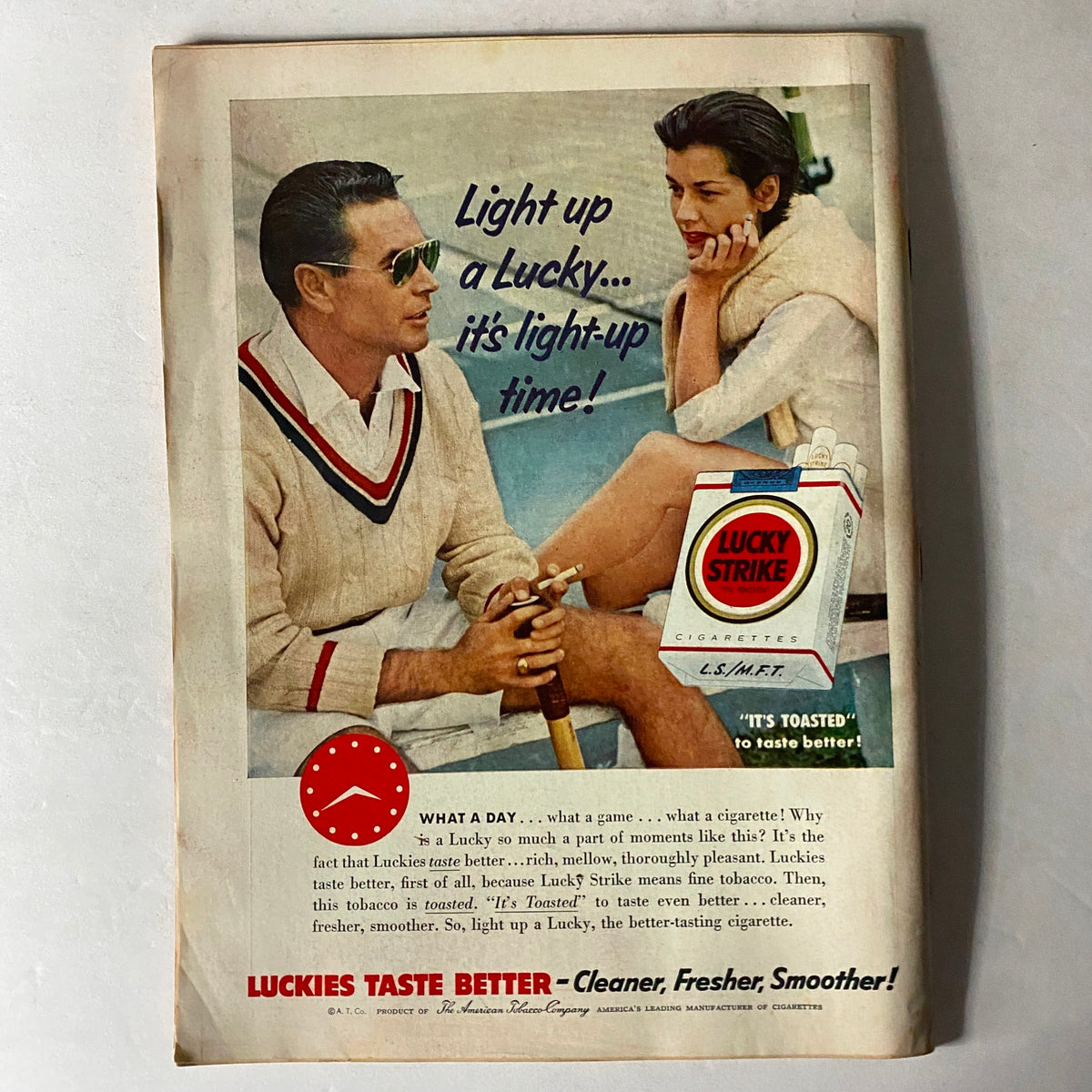 Advertisement for Lucky Strike cigarettes featuring a man and woman relaxing outdoors, promoting the slogan 'Light up a Lucky... it's light-up time!' from the mid-20th century.