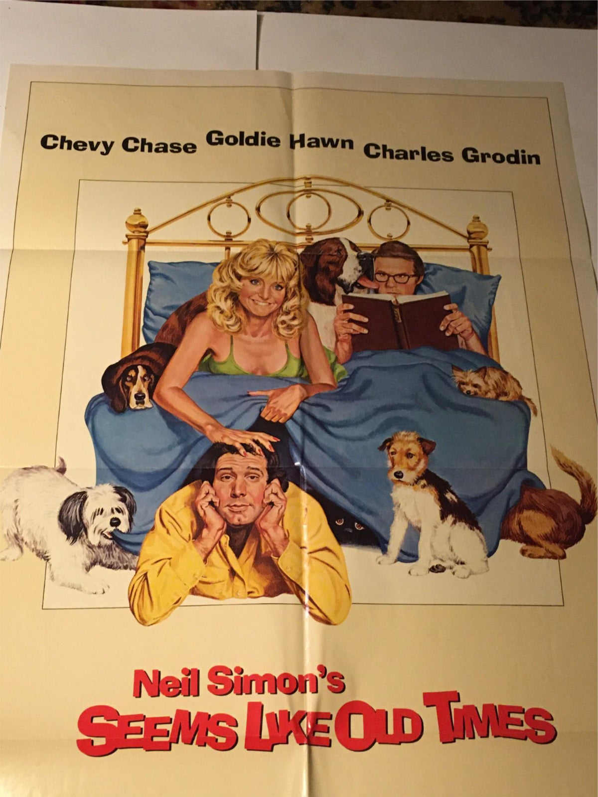 1980 Seems Like Old Times 41" x 27" Original Movie Poster illustration featuring Chevy Chase, Goldie Hawn, and Charles Grodin, displaying a comedic moment with dogs on a bed, perfect for film memorabilia collectors.