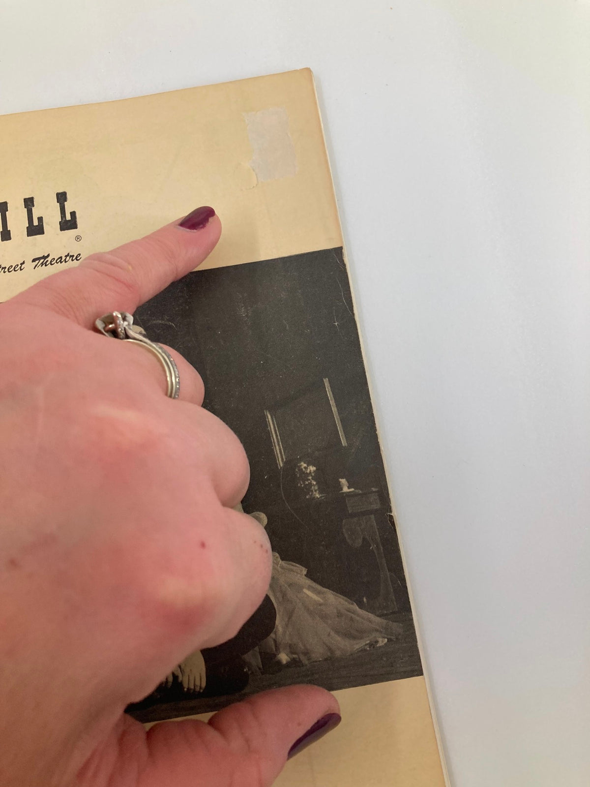 Close-up view of the 1949 Playbill for Regina at 46th Street Theatre, highlighting minor wear and a hand pointing at a small imperfection on the cover. This image shows the authenticity of the vintage theater artifact.