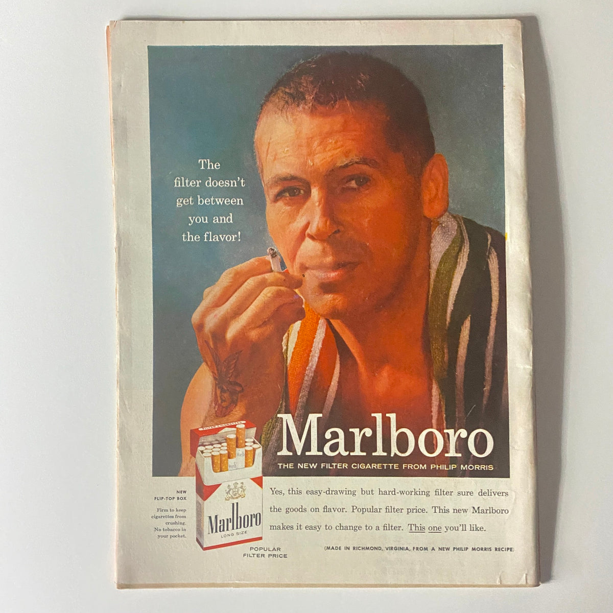 Classic Marlboro cigarette advertisement featuring a man with a towel, promoting the new filter cigarette, highlighting the phrase 'The filter doesn’t get between you and the flavor'.